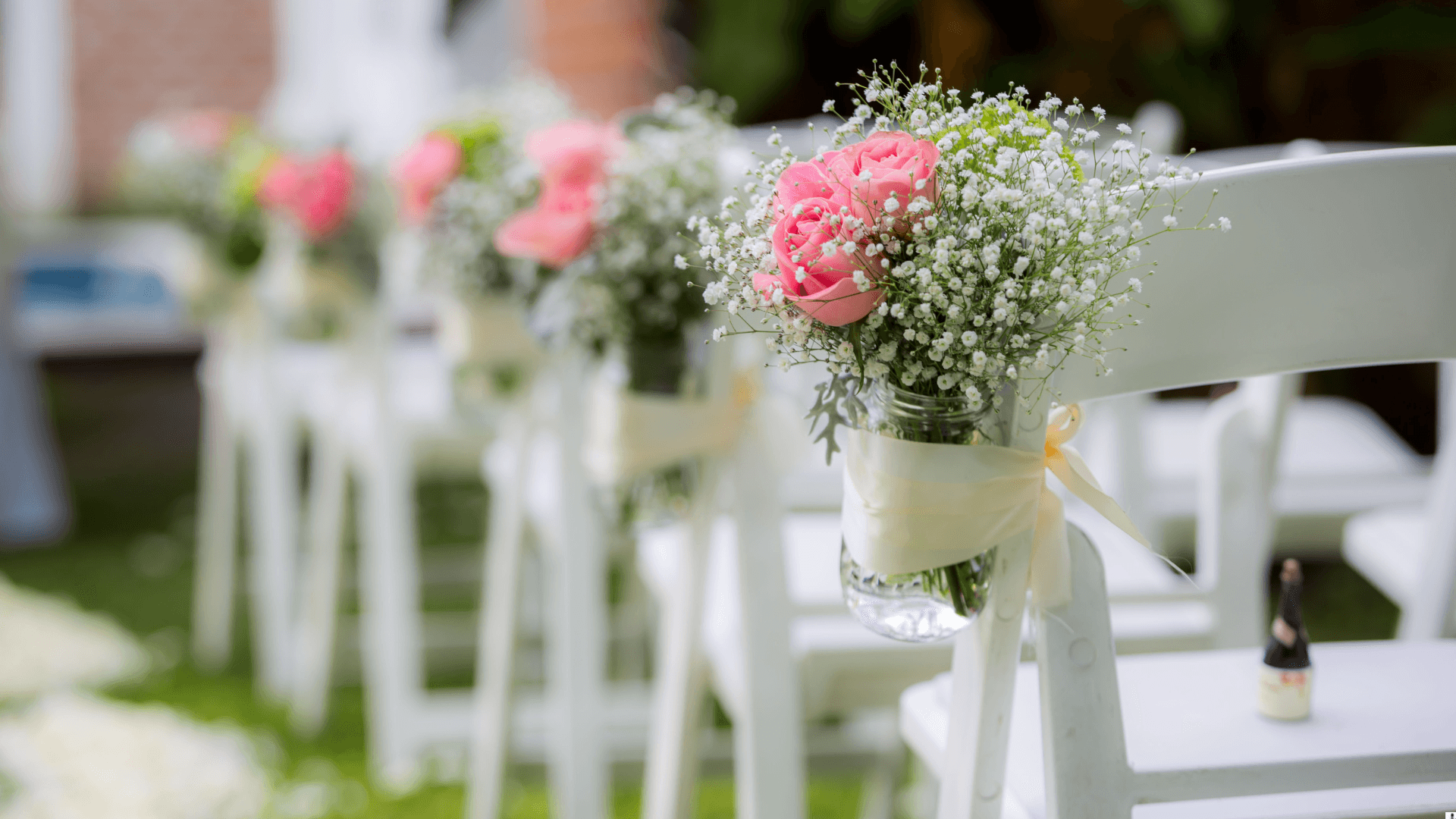 Outdoor ceremony chairs with pink floral accents