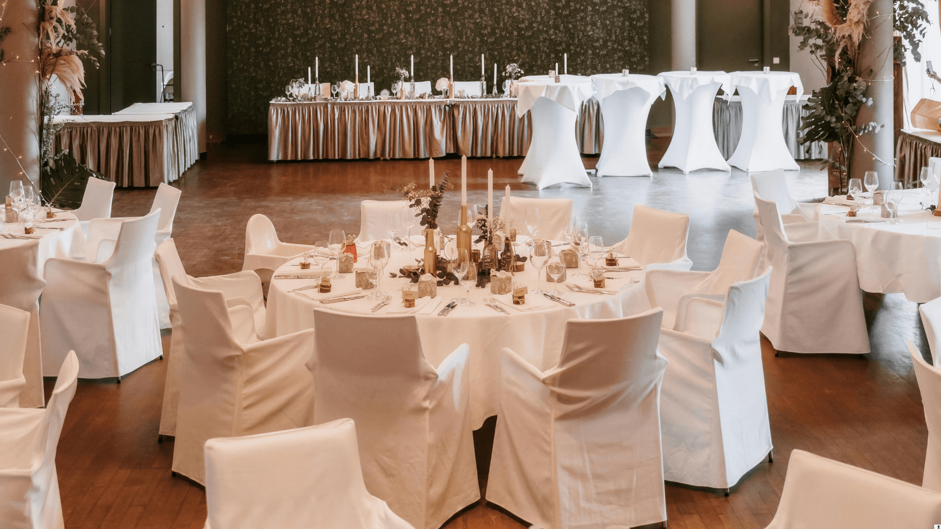 White ballroom with round tables and chair covers