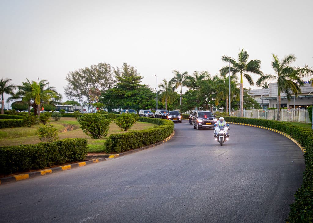 Motorcycle security escort leading a motorcade of black SUVs