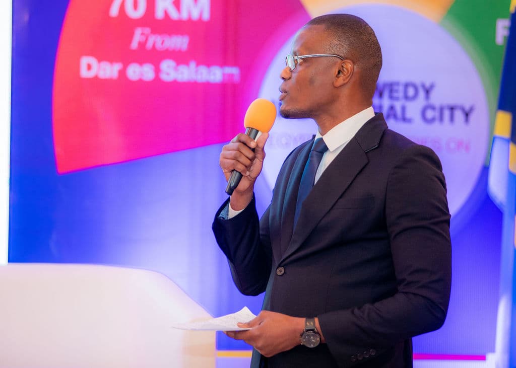 Moderator holding a microphone in front of a colourful investment infographic screen